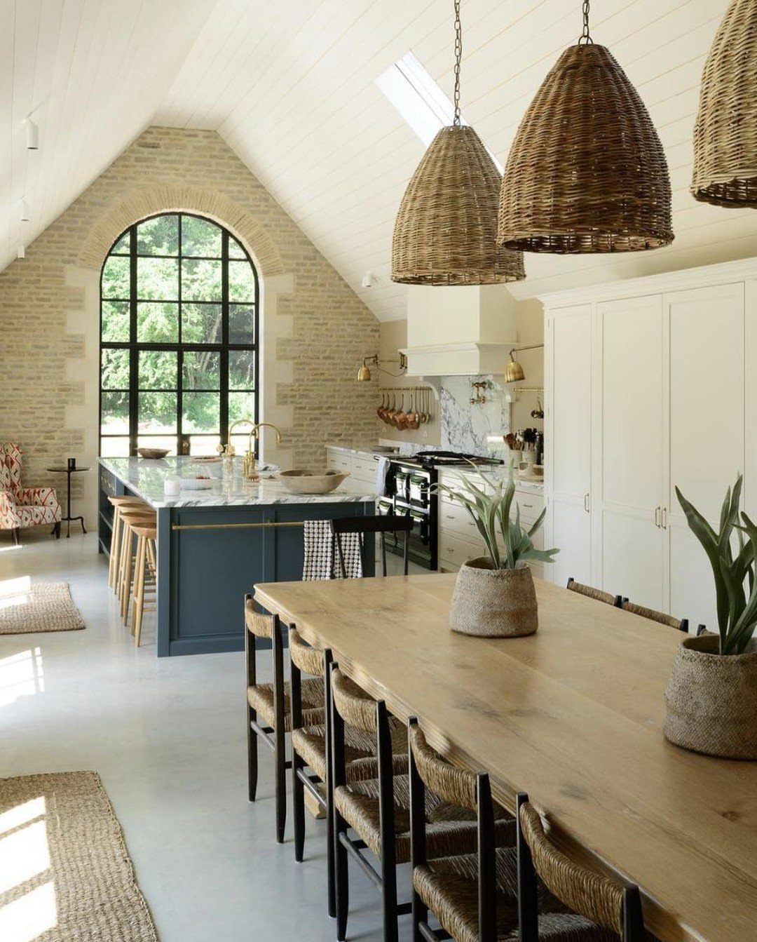 Light-colored exposed brick wall with a large arched window in a bright kitchen and dining room.
