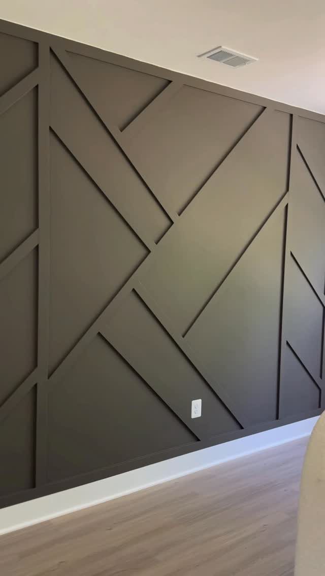 5 Wall Panelling for Living Room Ideas That Add Real Texture 3 Geometric dark grey wall panelling with diagonal and vertical wooden slats in a room.