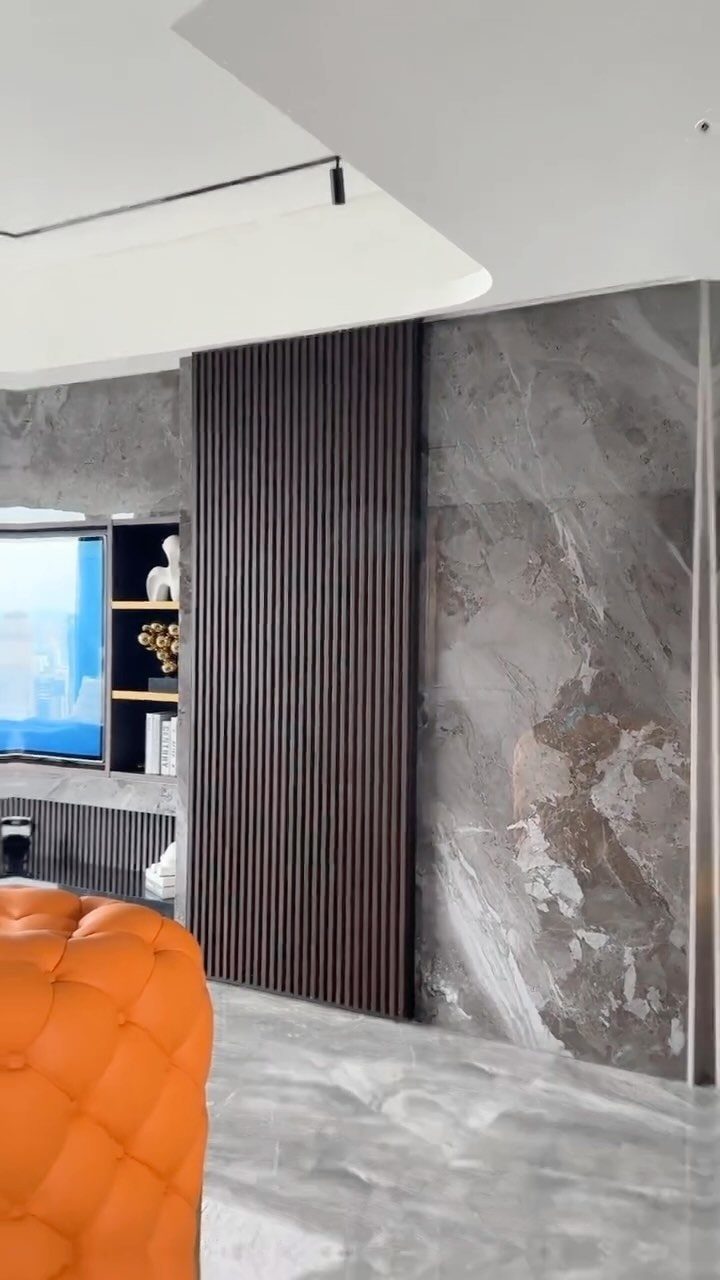 Dark brown wooden fluted wall panels installed between large grey marble slabs in a modern room.