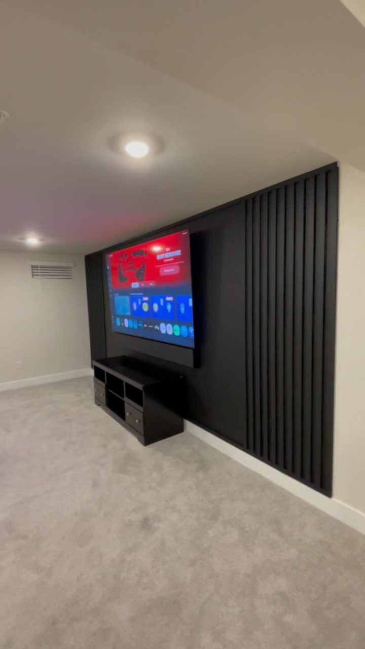 Black vertical wood slat accent wall with a mounted television and media console.