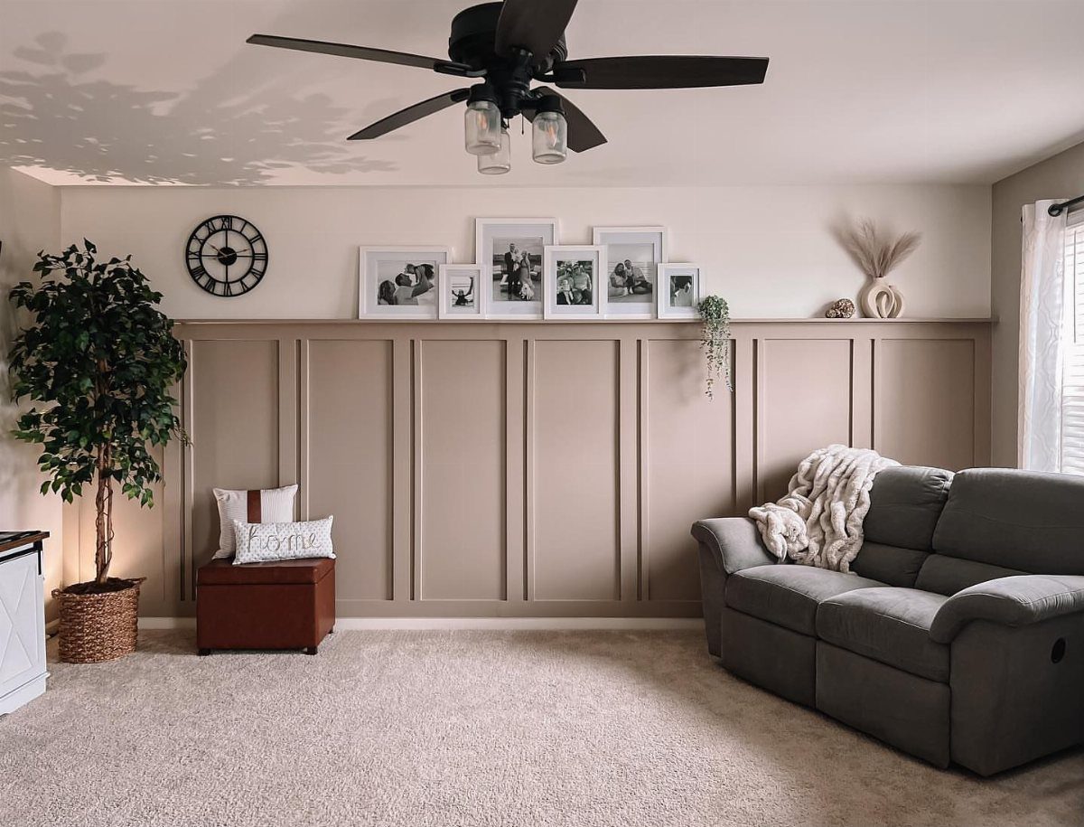 Beige board and batten accent wall in a living room with a grey sofa and plant.