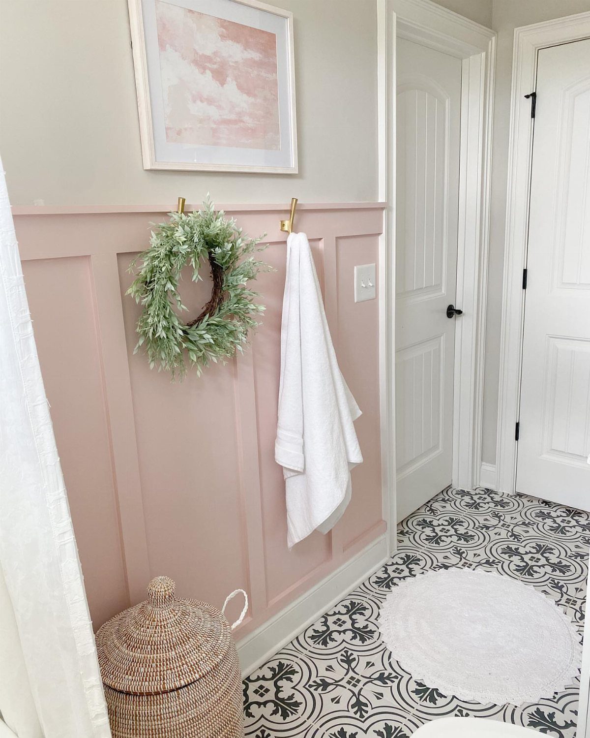 Pink board and batten wainscoting in a bathroom with patterned tile flooring and a white towel.