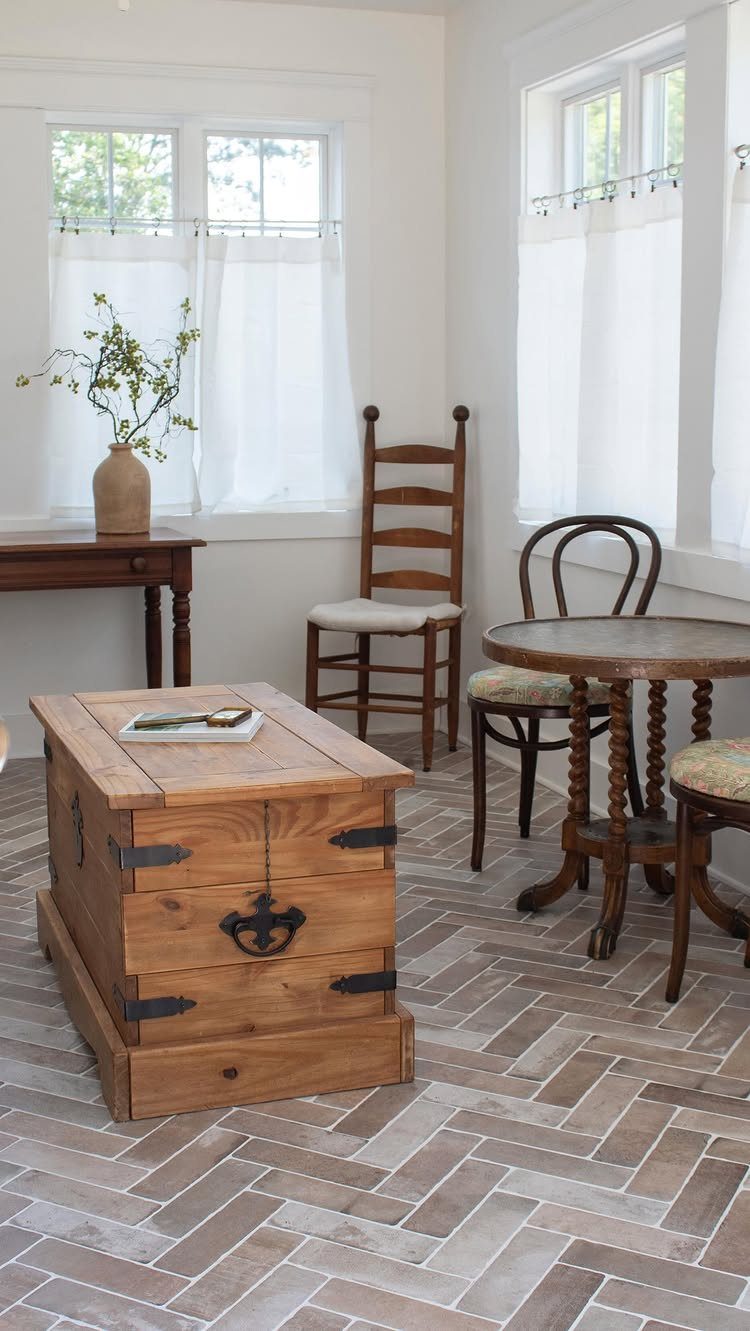 Brick-look tiles laid in a herringbone pattern on a floor in a furnished room.