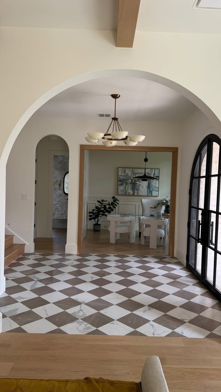Checkerboard pattern floor with white and taupe marble tiles seen through an arched doorway.