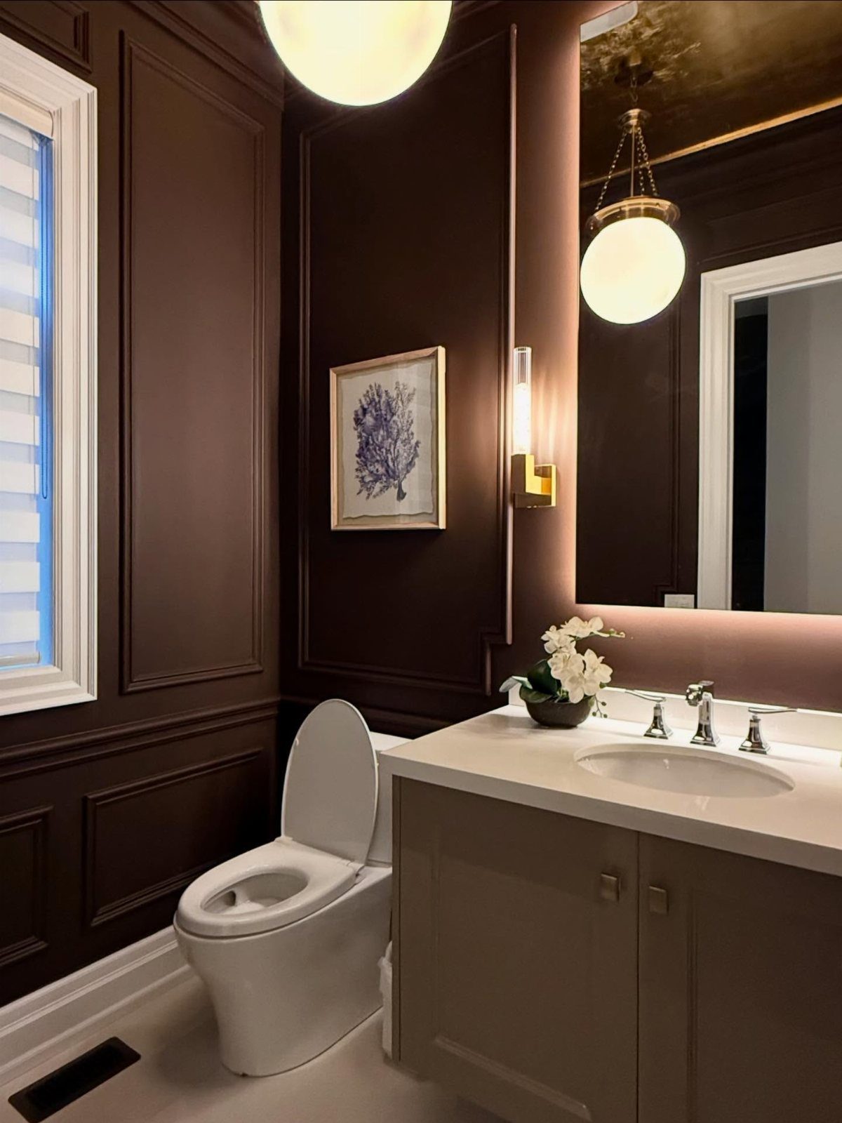 Dark brown paneled bathroom walls with a white toilet and vanity sink.