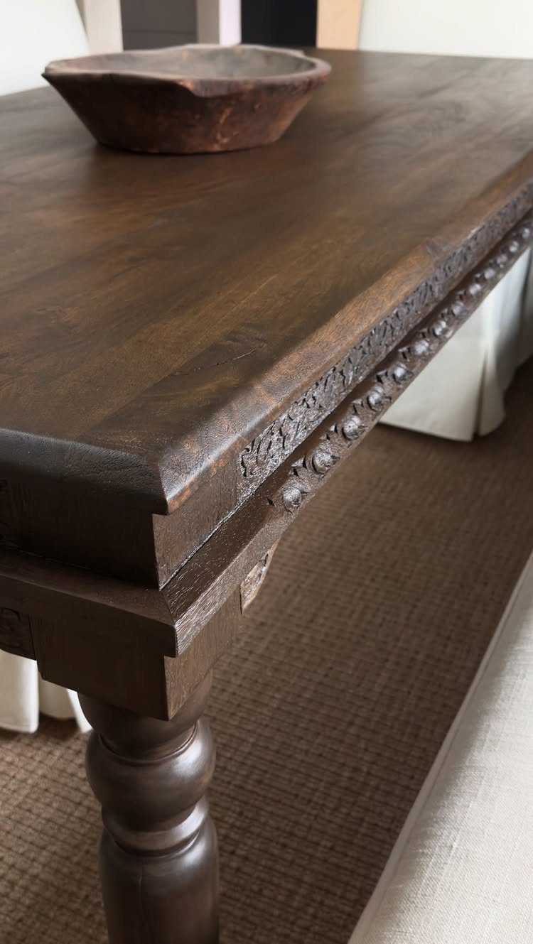 Dark Brown Wood Colors: 13 Ideas for Your Home 8 Dark brown wooden dining table with carved edges and a small rustic bowl on top.