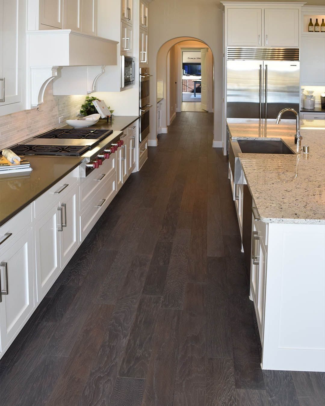Dark stained wood flooring running through a bright, modern kitchen with white cabinets.