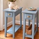 Two narrow light blue end tables with drawers and lower shelves on wooden flooring.