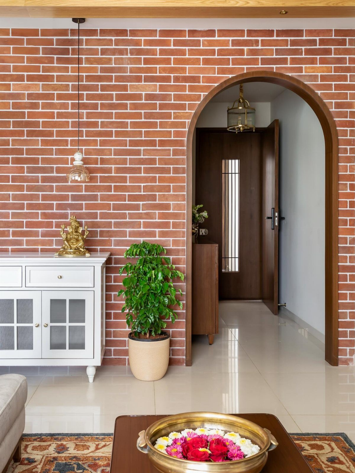 A red brick accent wall with an arched doorway and a white sideboard.
