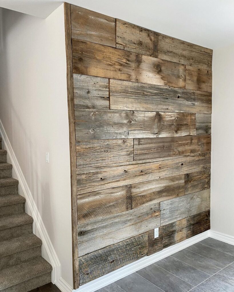 Reclaimed wood planks covering a wall in a home hallway next to stairs.
