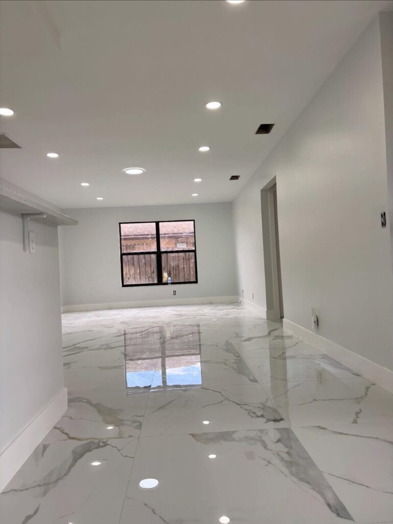 Polished white marble tiles with grey veining covering the floor of an empty room.