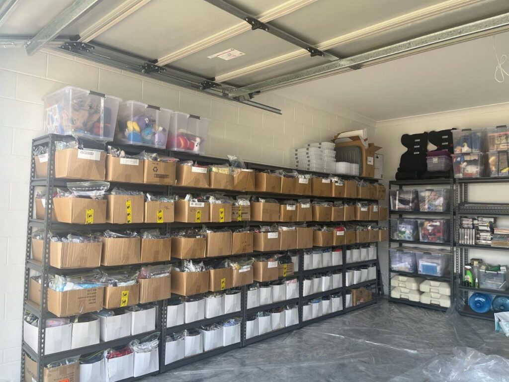 Metal shelving units in a garage organized with cardboard boxes and storage bins.