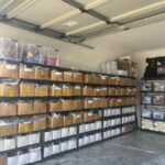 Metal shelving units in a garage organized with cardboard boxes and storage bins.