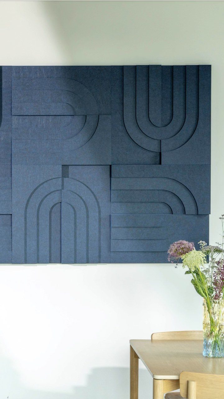 Blue geometric acoustic panel with embossed arch patterns mounted on a white wall.