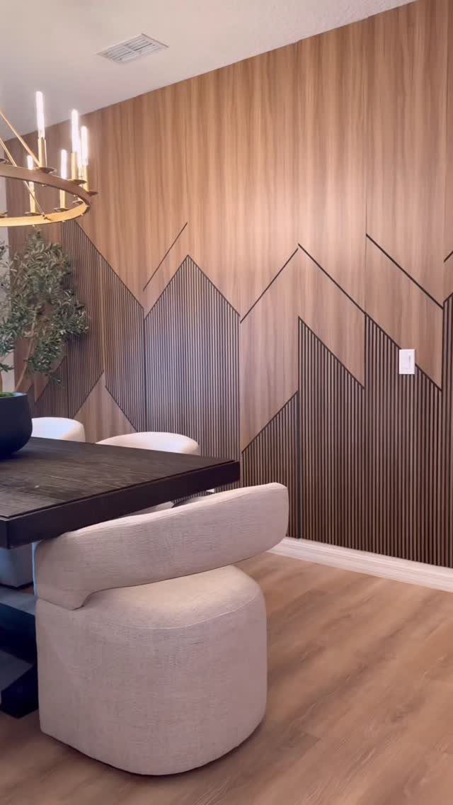 Geometric mountain pattern accent wall with vertical wood slats in a dining room setting.