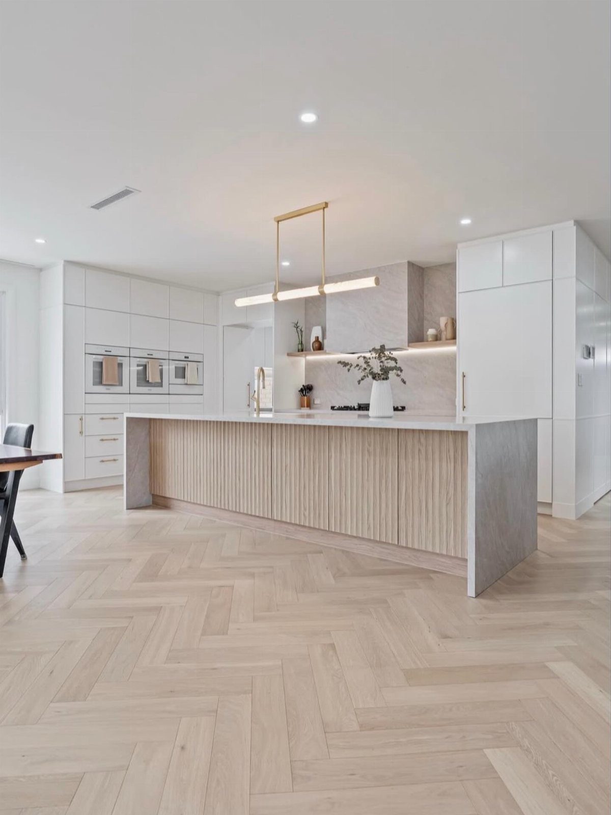 Light wood herringbone flooring in a bright, modern kitchen with a large central island.