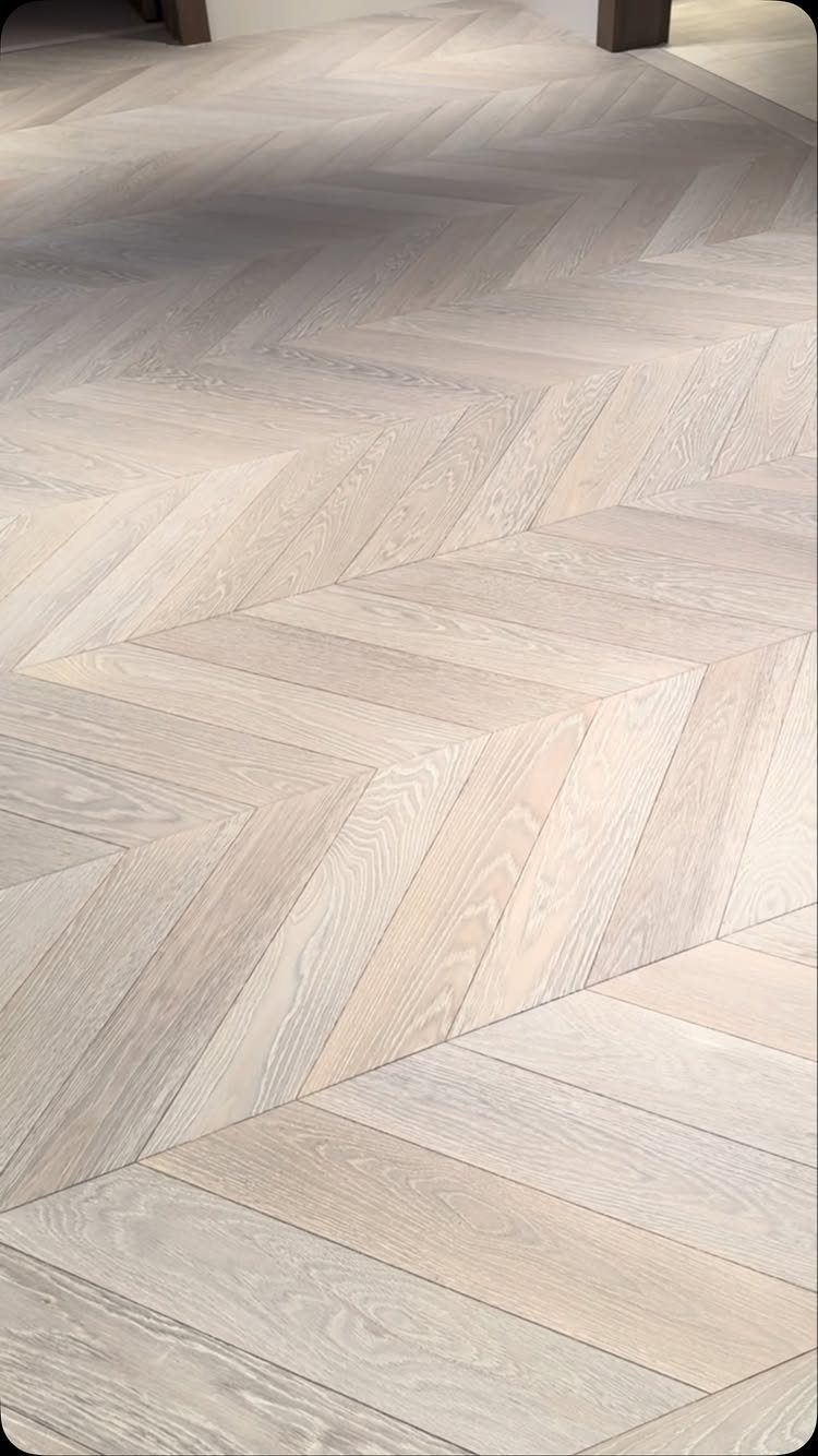 Light creamy maple wood flooring planks arranged in a herringbone pattern.