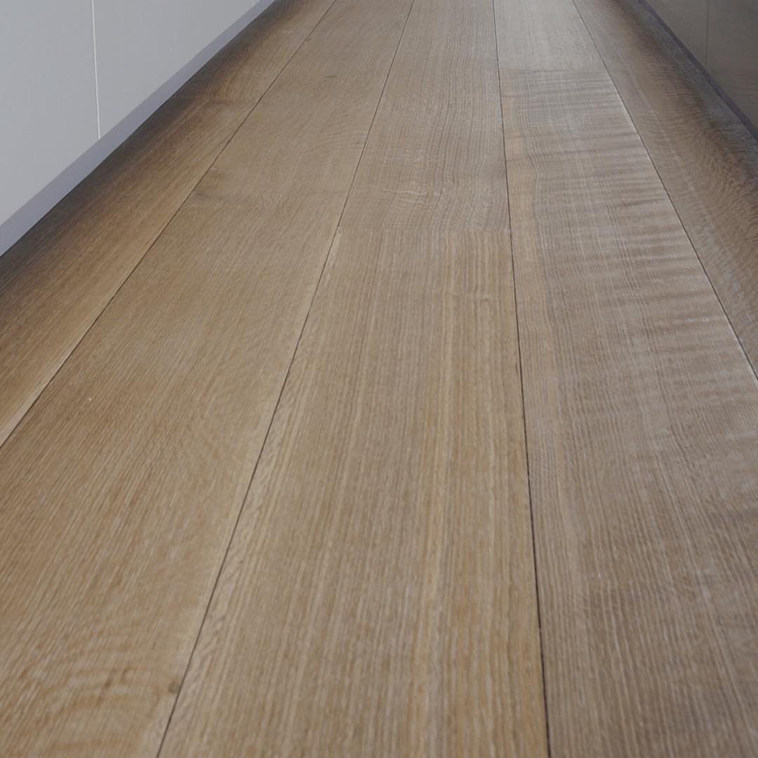 Light brown wooden floor planks with natural grain running through a bright hallway.