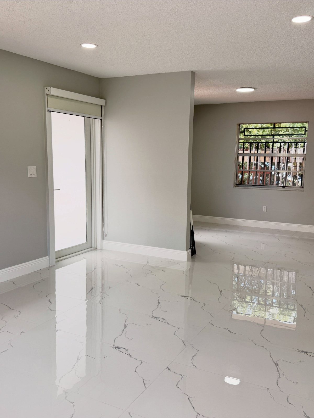 Polished white marble-look floor tiles with grey veining in a bright, modern room.
