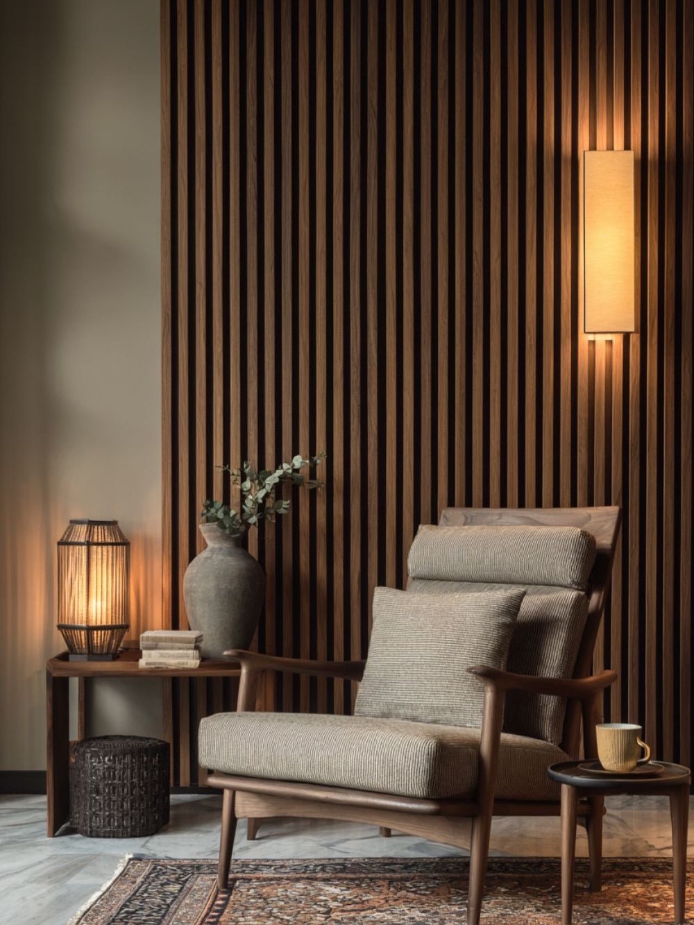 Vertical dark wood slats covering a wall behind a wooden armchair and side table.