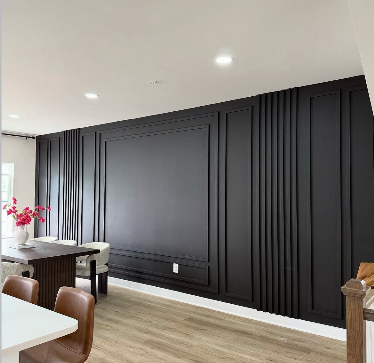 Black decorative wall paneling with vertical slats and rectangular molding in a modern dining room.
