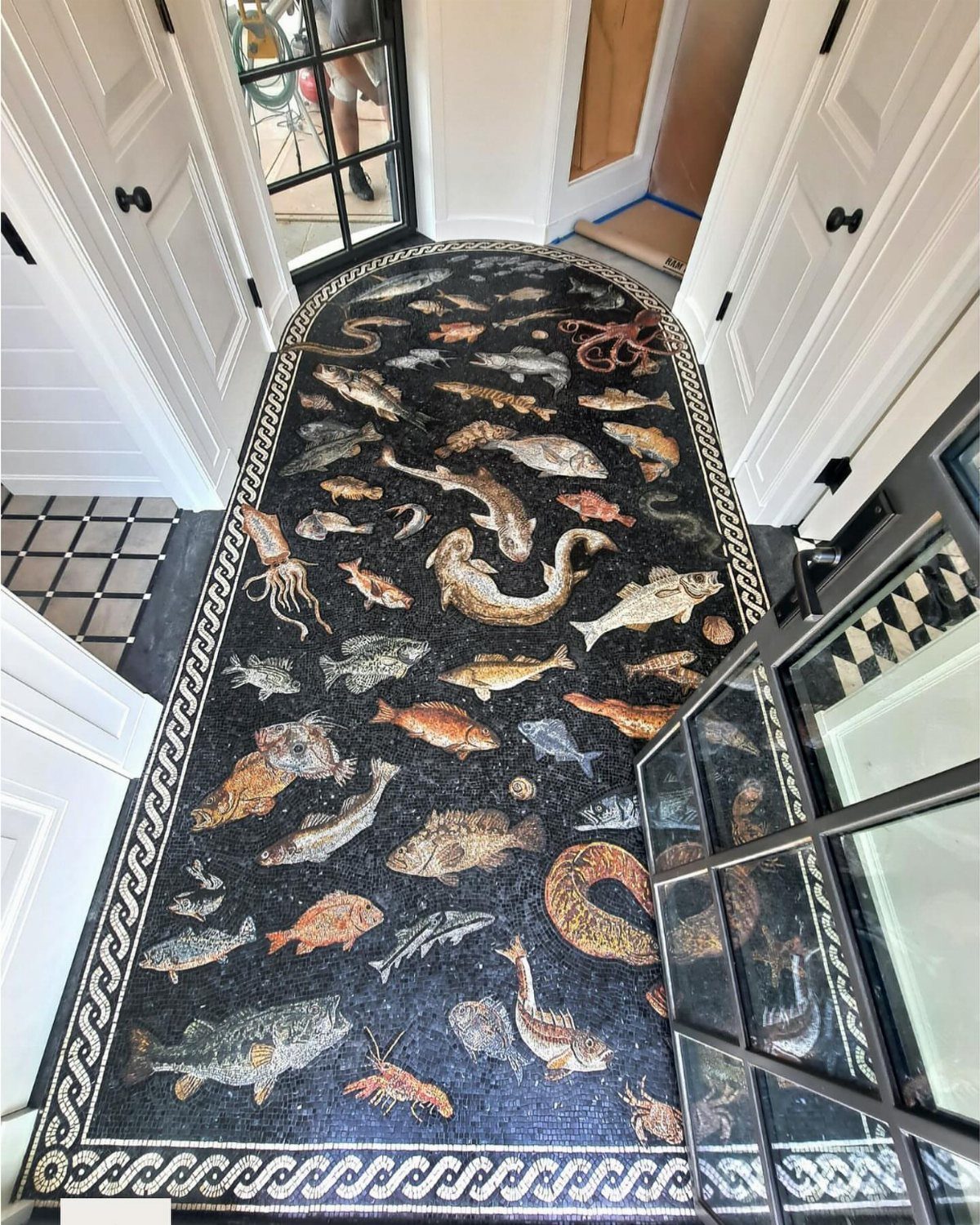 Intricate mosaic tile floor depicting various colorful sea creatures and fish in a dark hallway.