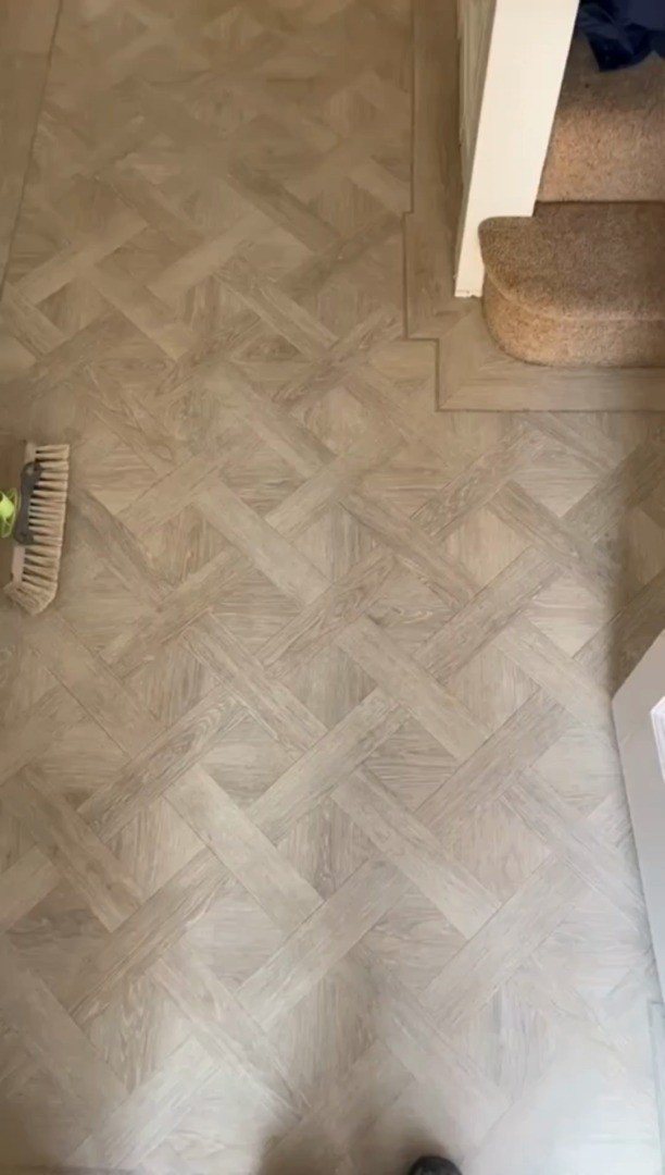 Light brown wood-effect planks arranged in a basket weave pattern on a floor.