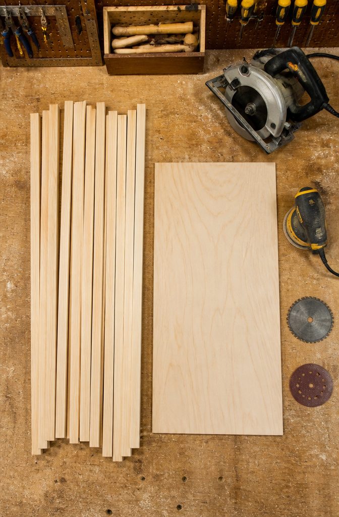 Pine 1x2 boards stacked on a workbench for slat wall construction.