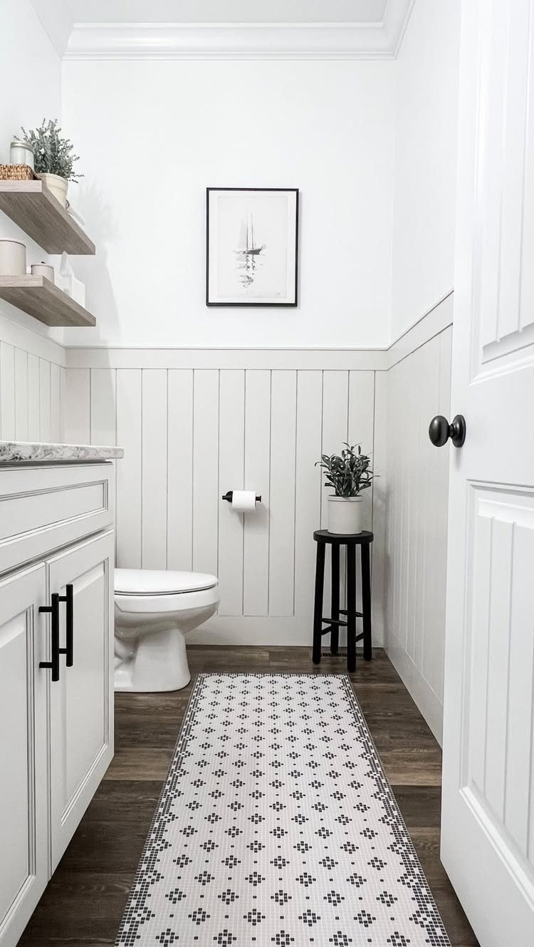 White vertical wainscoting panels in a small bathroom with a toilet and patterned rug.