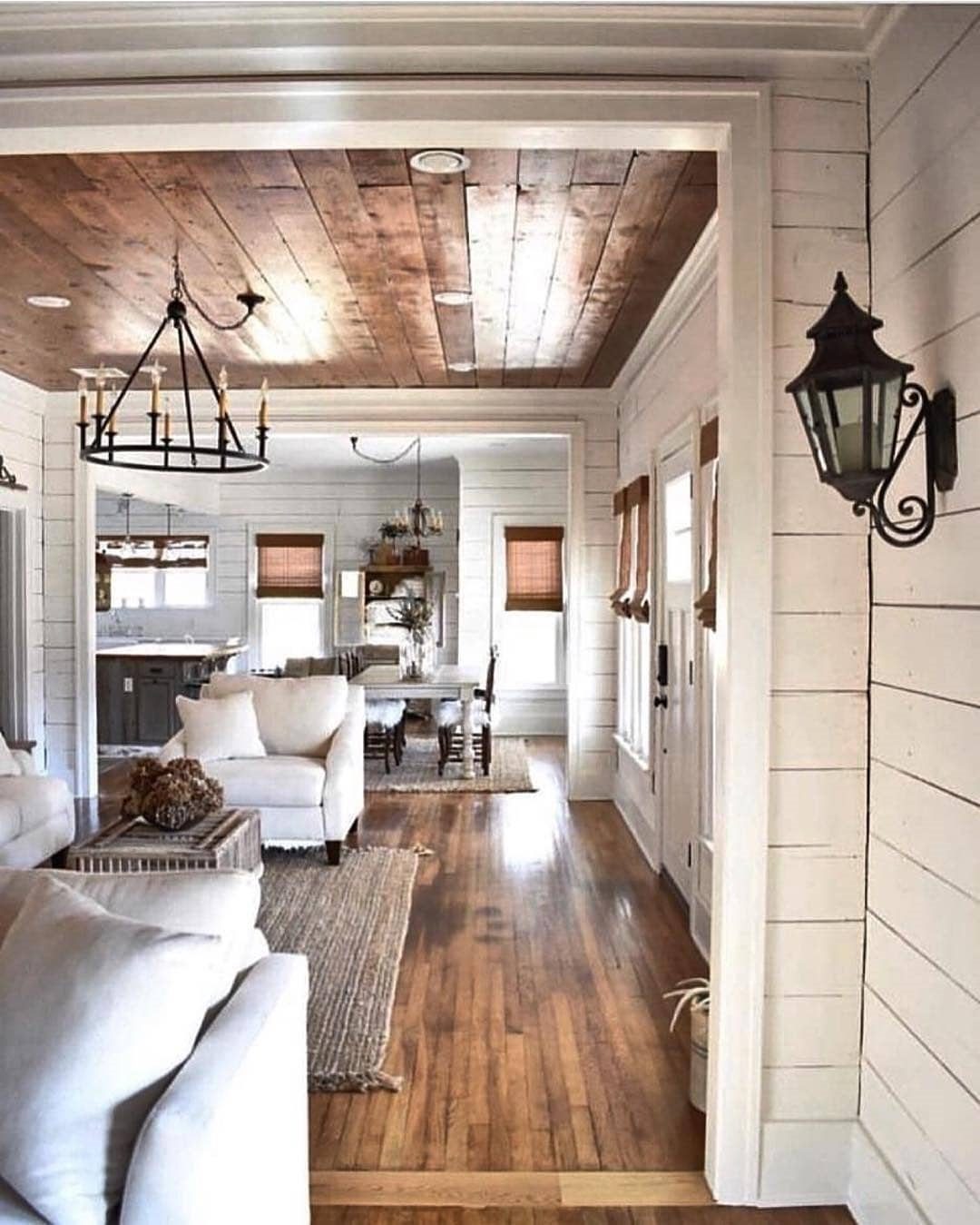 White shiplap walls in a bright living room with wooden ceilings and hardwood floors.