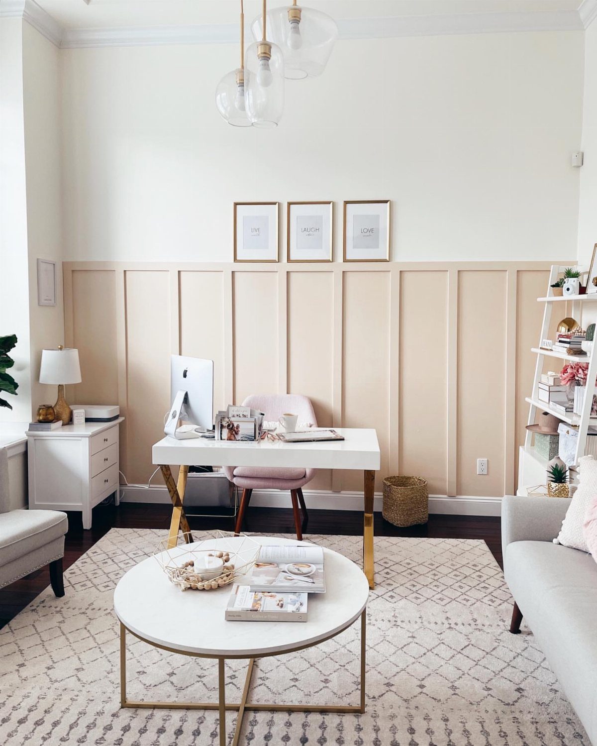 White desk and pink chair positioned in front of a beige board and batten accent wall.