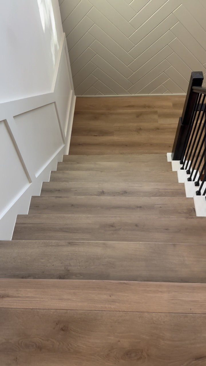 Light brown wooden stairs leading down to a landing with white paneled walls.