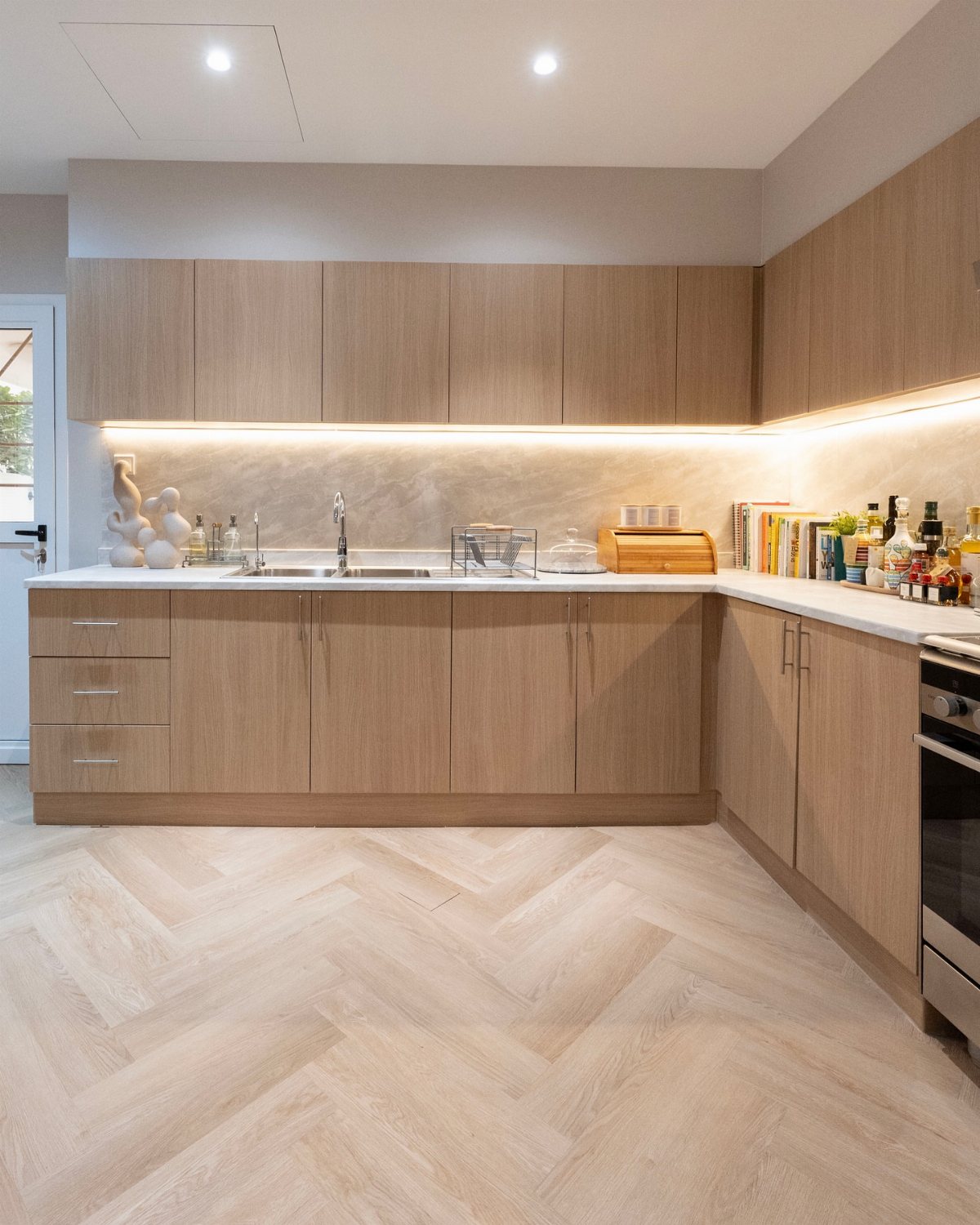 Vinyl Flooring with Oak Cabinets: 3 Ways to Make It Work 2 Light oak kitchen cabinets paired with herringbone pattern vinyl flooring in a modern kitchen.