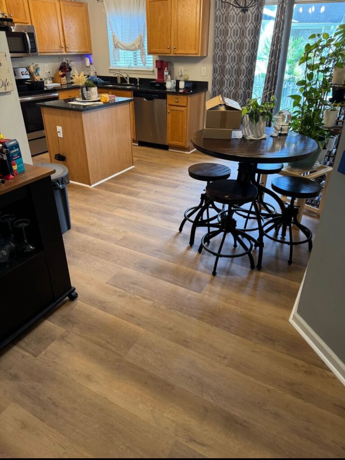 Vinyl Flooring with Oak Cabinets: 3 Ways to Make It Work 3 Light wood-look vinyl flooring stretches across a kitchen with oak cabinets and a dining set.