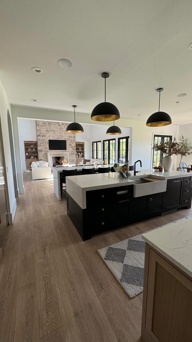 Light wood flooring in a modern kitchen with black islands and pendant lighting.