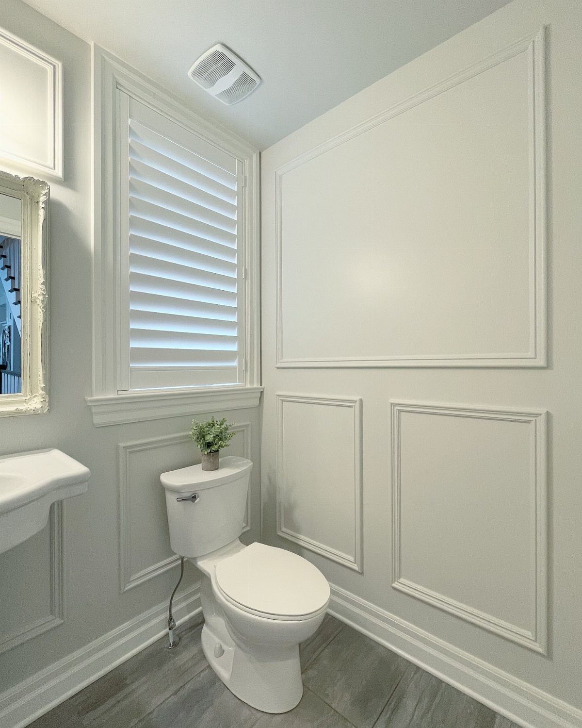 White wainscoting panels installed on light gray bathroom walls near a white toilet.